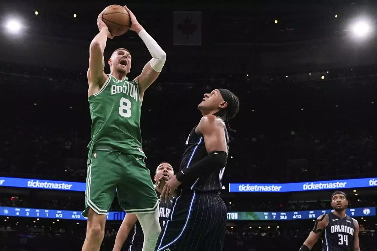 Boston Celtics center Kristaps Porzingis (8) grabs a rebound against Orlando Magic forward Paolo Banchero, right, during the first half in game 2 of a first-round NBA playoff basketball series, Wednesday, April 23, 2025, in Boston. (AP Photo/Charles Krupa)