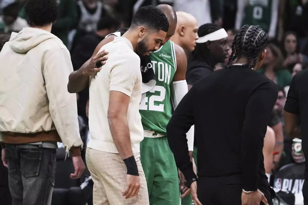 Boston Celtics forward Jayson Tatum, who is sidelined with an injury, gets a pat on the back from center Al Horford during the first half in game 2 of a first-round NBA playoff basketball series, Wednesday, April 23, 2025, in Boston. (AP Photo/Charles Krupa)