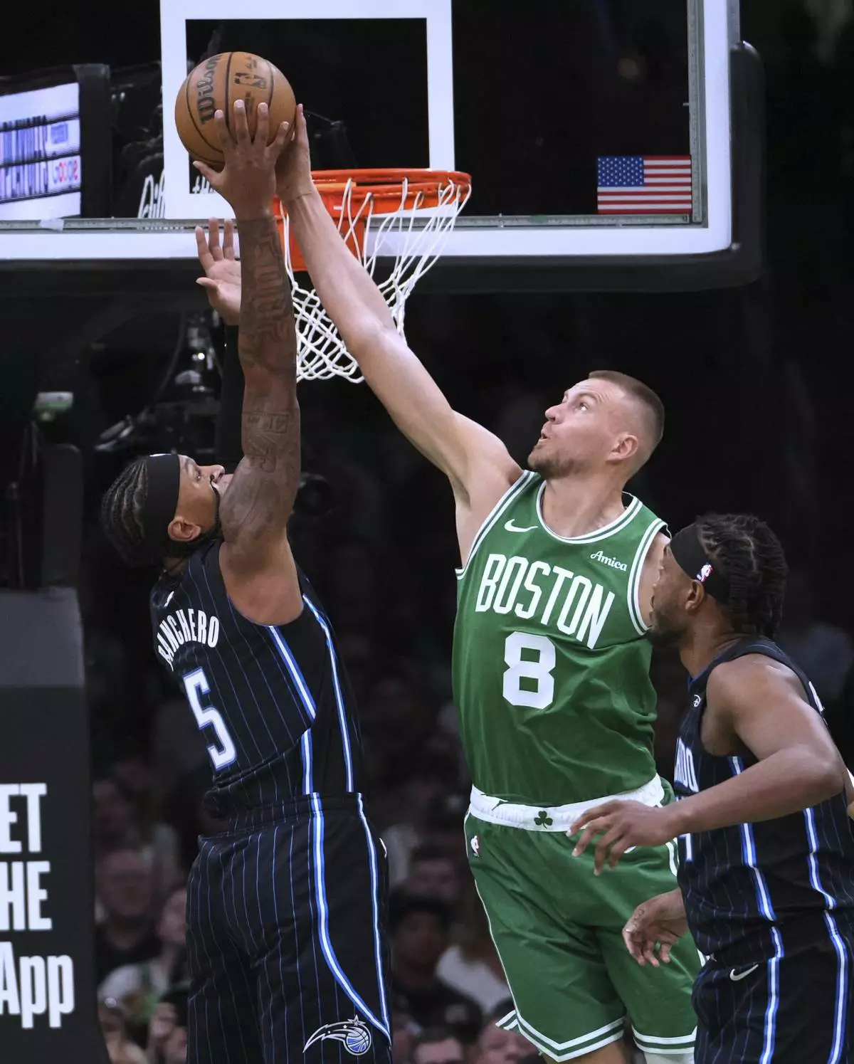 Boston Celtics center Kristaps Porzingis (8) blocks a shot by Orlando Magic forward Paolo Banchero (5) during the first half in game 2 of a first-round NBA playoff basketball series, Wednesday, April 23, 2025, in Boston. (AP Photo/Charles Krupa)
