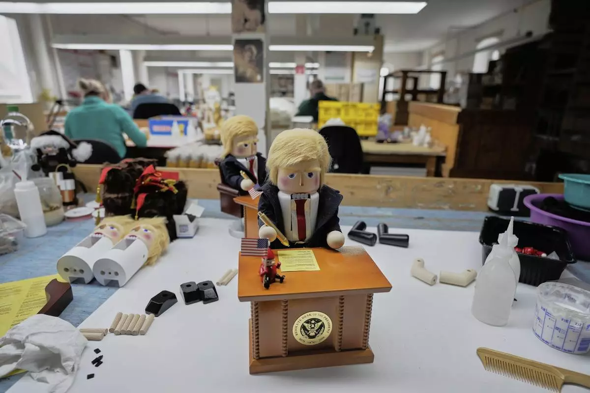 The limited-edition nutcrackers titled "Resolute Desk of the President," featuring a seated figure signing a "presidential proclamation," is seen at the Steinbach-Volkskunst nutcracker factory in Marienberg, Germany, Tuesday, April 15, 2025. (AP Photo/Markus Schreiber)
