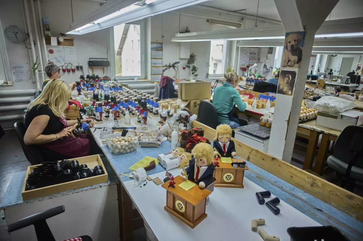 Two limited-edition nutcrackers titled "Resolute Desk of the President," featuring a seated figure signing a "presidential proclamation," are seen on a table at the Steinbach-Volkskunst nutcracker factory in Marienberg, Germany, Tuesday, April 15, 2025. (AP Photo/Markus Schreiber)