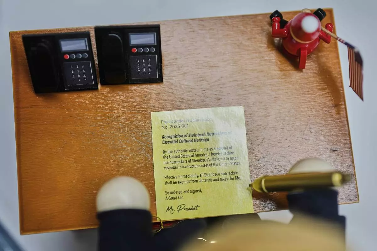 The desk of the limited-edition nutcracker titled "Resolute Desk of the President," featuring a seated figure signing a "presidential proclamation," is seen at the Steinbach-Volkskunst nutcracker factory in Marienberg, Germany, Tuesday, April 15, 2025. (AP Photo/Markus Schreiber)