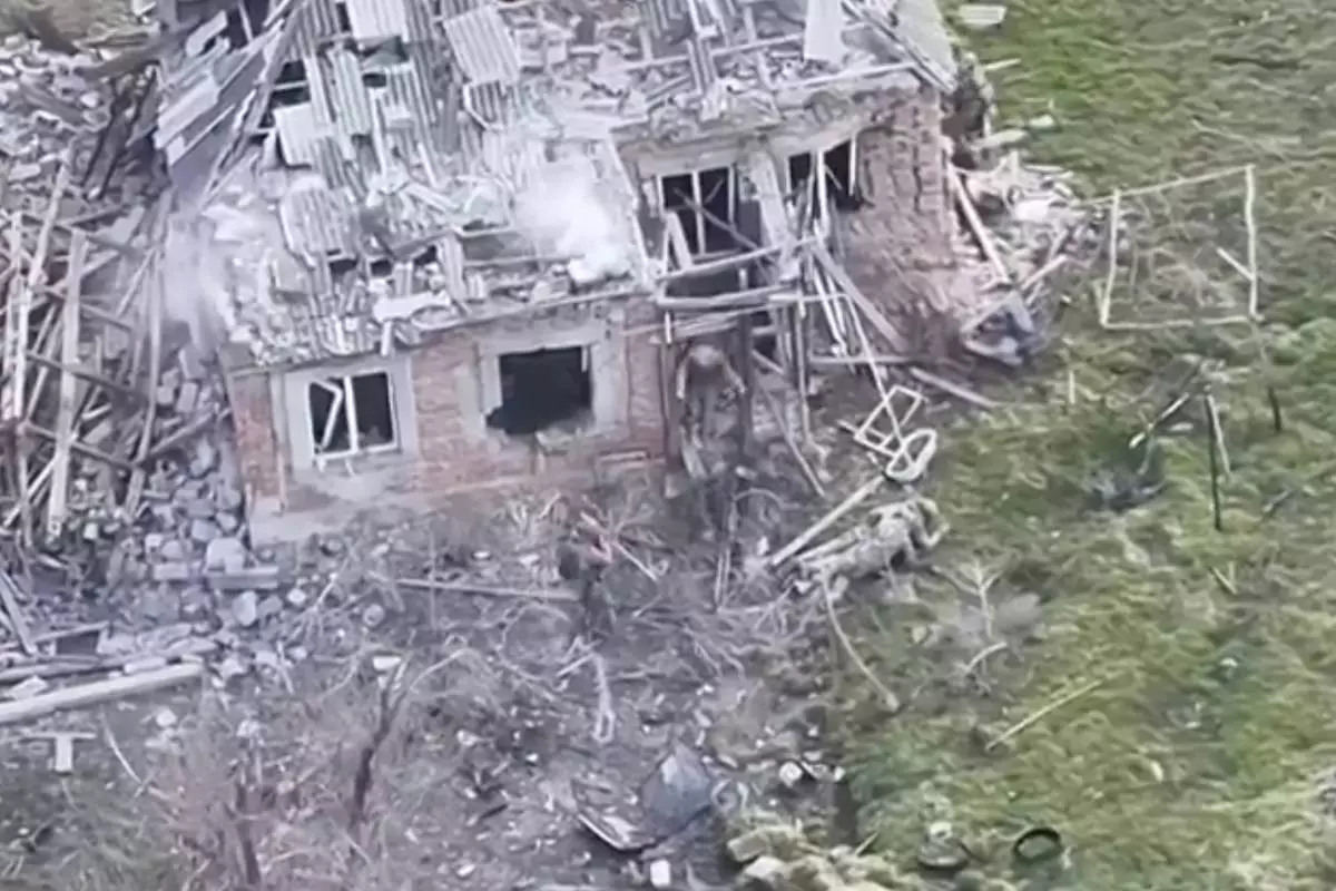 This image taken from video that European military officials say was filmed by a Ukrainian drone in the southern Ukrainian village of Piatykhatky on March 13, 2025, shows a soldier, left, identified as Russian, pointing his gun at a Ukrainian soldier who appears to be surrendering after emerging from the ruins of a house to join other Ukrainian prisoners on the ground. (Ukraine Military/European Defense Officials via AP)