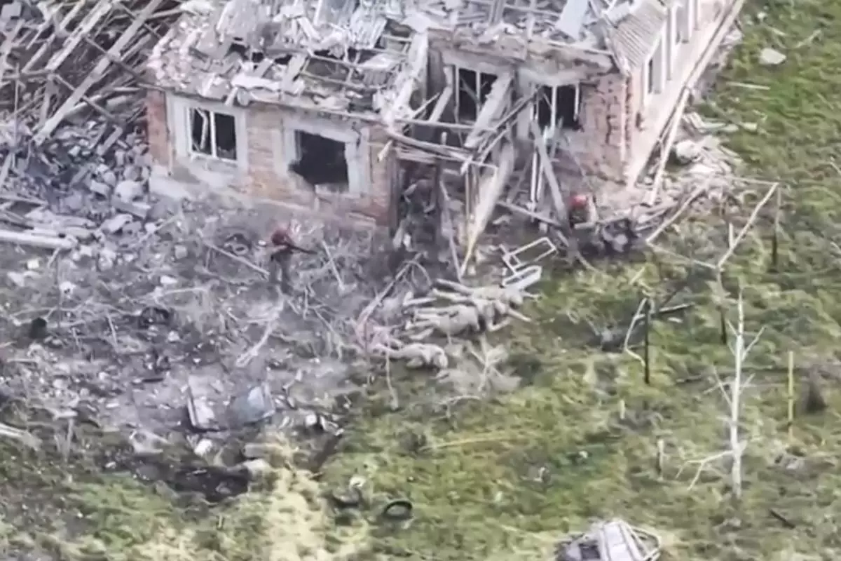 This image taken from video that European military officials say was filmed by a Ukrainian drone in the southern Ukrainian village of Piatykhatky on March 13, 2025, shows three soldiers with red helmets and uniform markings identified as Russian surrounding four Ukrainian soldiers who appear to have surrendered and are laying on the ground. (Ukraine Military/European Defense Officials via AP)