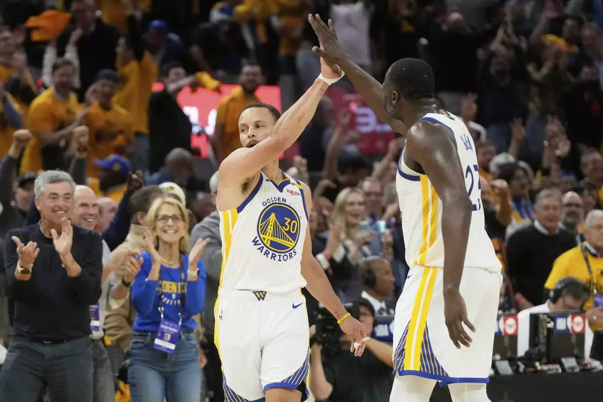 Golden State Warriors guard Stephen Curry (30) is congratulated by forward Draymond Green after making a 3-point basket during the second half of an NBA play-in tournament basketball game against the Memphis Grizzlies in San Francisco, Tuesday, April 15, 2025. (AP Photo/Jeff Chiu)