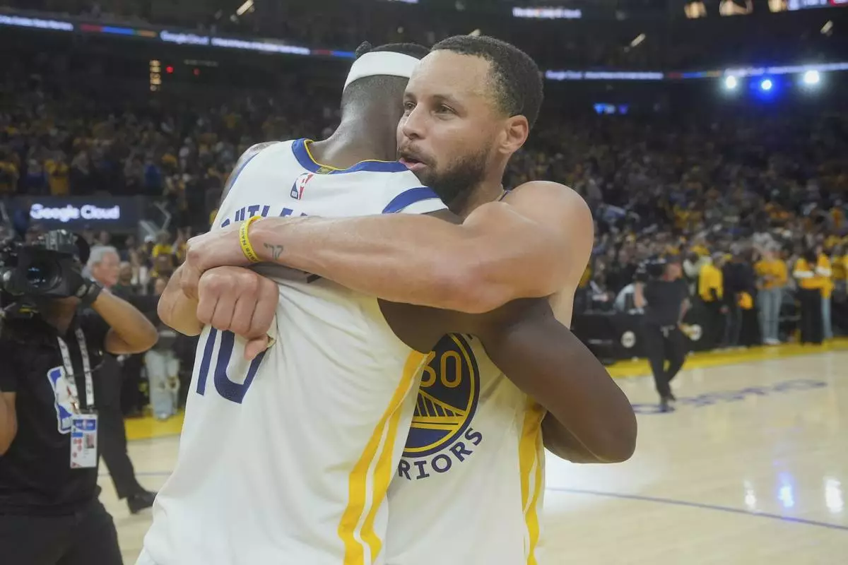 Golden State Warriors forward Jimmy Butler III, left, celebrates with guard Stephen Curry after an NBA play-in tournament basketball game against the Memphis Grizzlies in San Francisco, Tuesday, April 15, 2025. (AP Photo/Jeff Chiu)