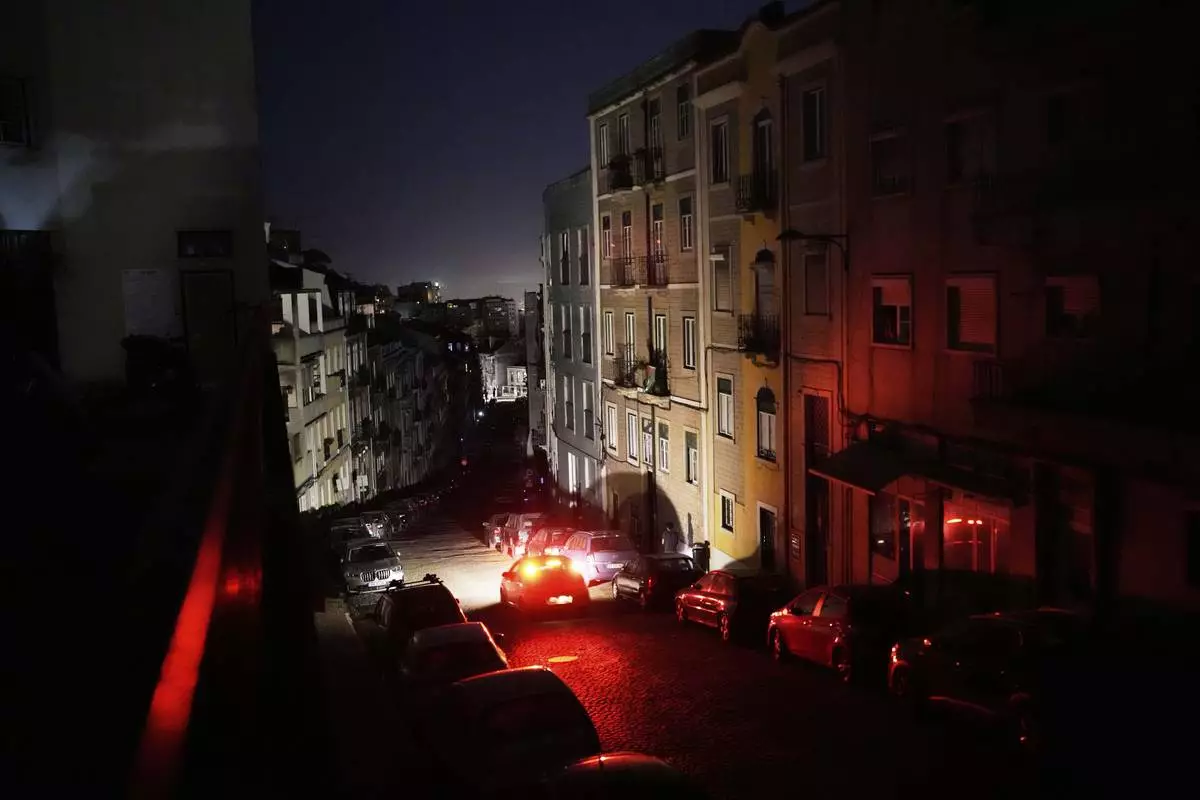 A car drives down an unlit street in Lisbon, during a nationwide power outage, Monday night, April 28, 2025. (AP Photo/Armando Franca)