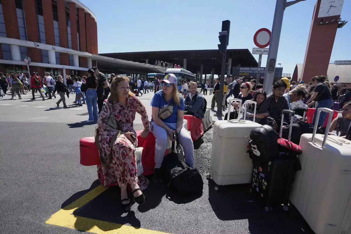 Passengers wait outside Atocha train station during a nationwide power outage in Madrid, Monday, April 28, 2025. (AP Photo/Manu Fernandez)