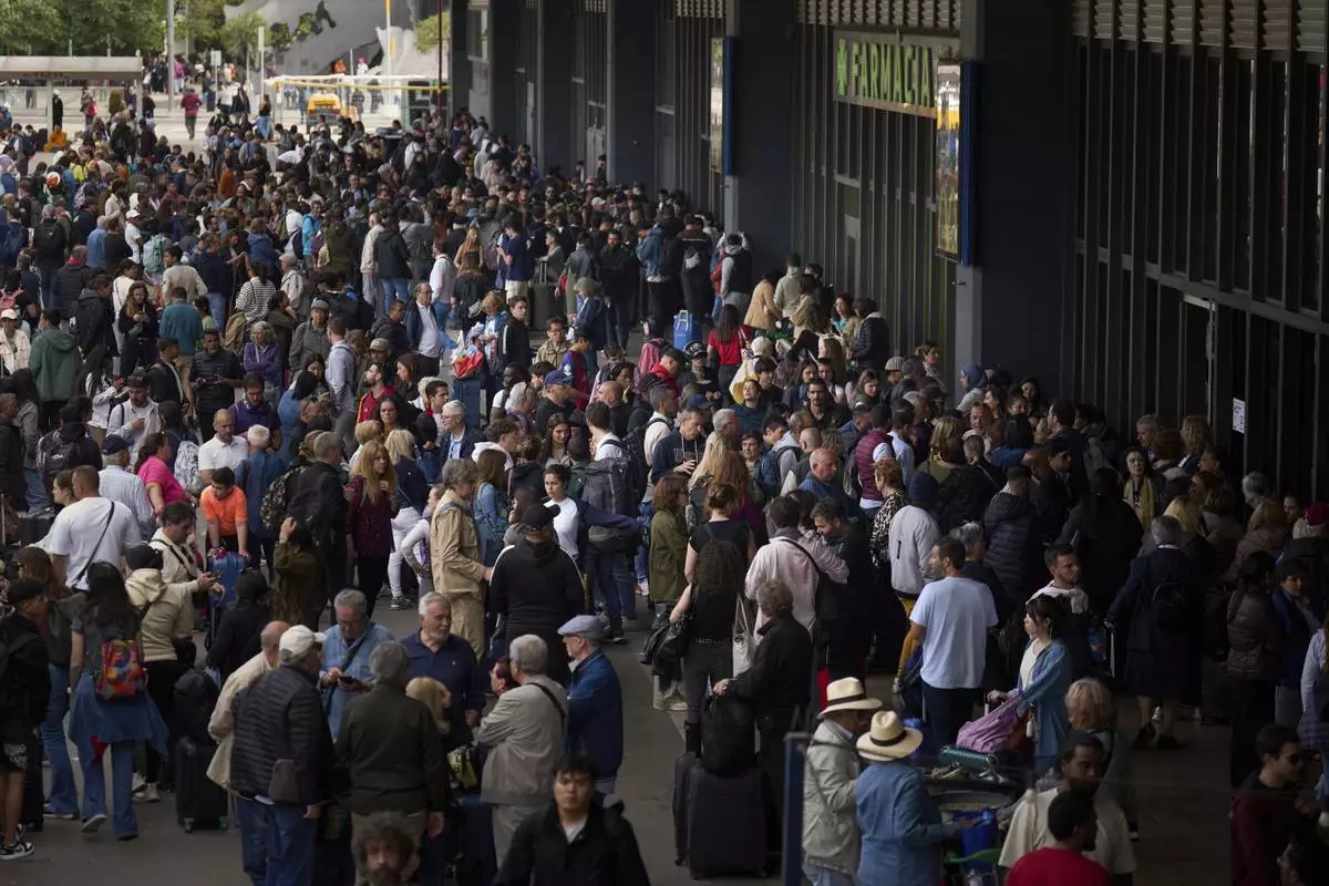 People wait outside a closed train station, during a major power outage in Barcelona, Spain, Monday, April 28, 2025. (AP Photo/Emilio Morenatti)