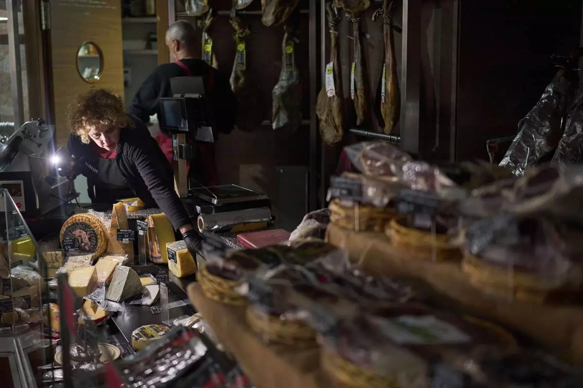 Vendors use their phone light to select and save some food, during a major power outage in Barcelona, Spain, Monday, April 28, 2025. (AP Photo/Emilio Morenatti)