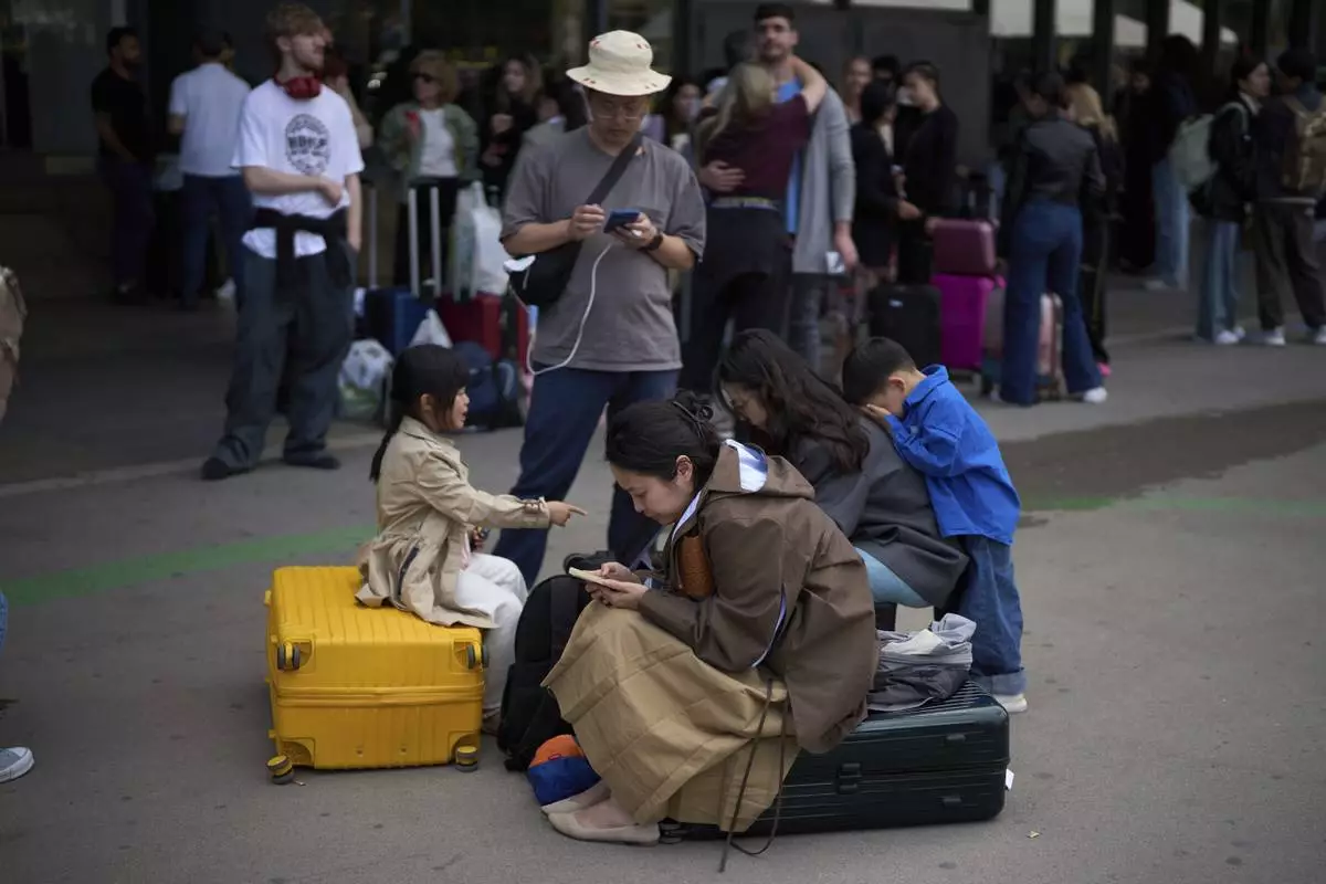 People wait outside a closed train station, during a major power outage in Barcelona, Spain, Monday, April 28, 2025. (AP Photo/Emilio Morenatti)