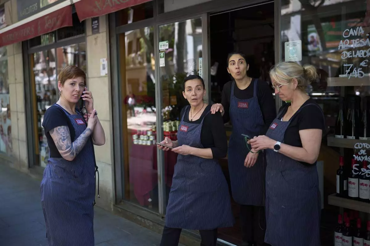 Vendors react outside their shop, during a major power outage in Barcelona, Spain, Monday, April 28, 2025. (AP Photo/Emilio Morenatti)