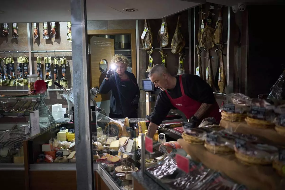 Vendors use their phone light to select and save some food, during a major power outage in Barcelona, Spain, Monday, April 28, 2025. (AP Photo/Emilio Morenatti)