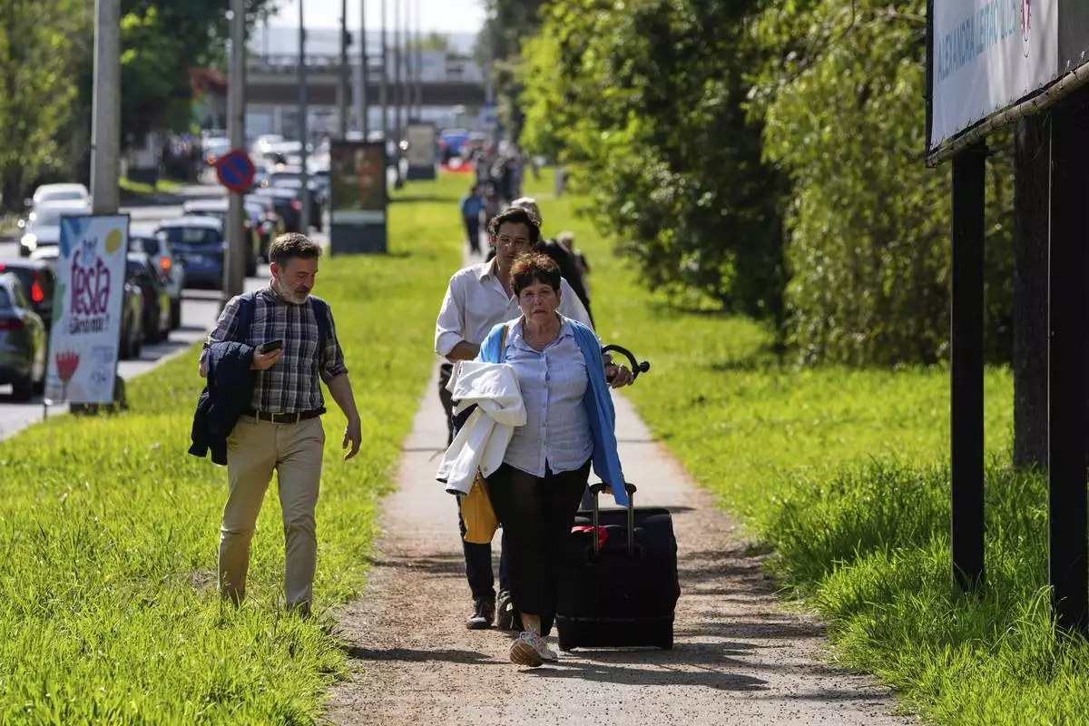 Passengers walk towards Lisbon Airport during a nationwide power outage in Lisbon, Monday, April 28, 2025. (AP Photo/Armando Franca)