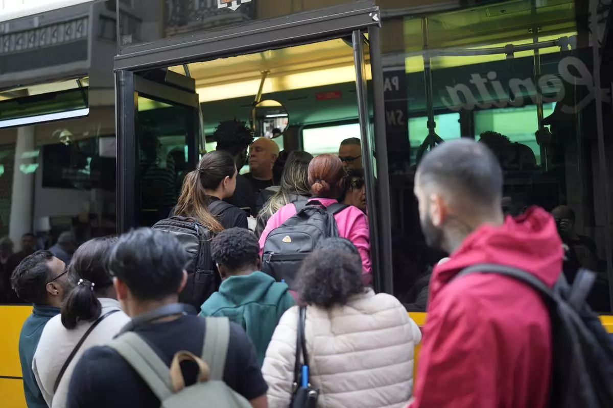 People try to board a crowded bus after the subway stopped running following a power outage in Lisbon, Portugal, Monday, April 28, 2025. (AP Photo/Armando Franca)