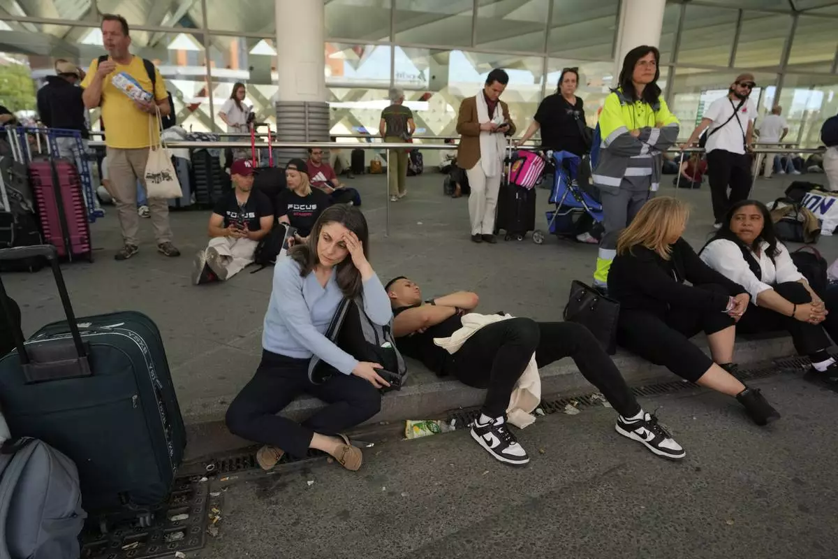 Passengers wait outside Atocha train station during a nationwide power outage in Madrid, Monday, April 28, 2025. (AP Photo/Manu Fernandez)