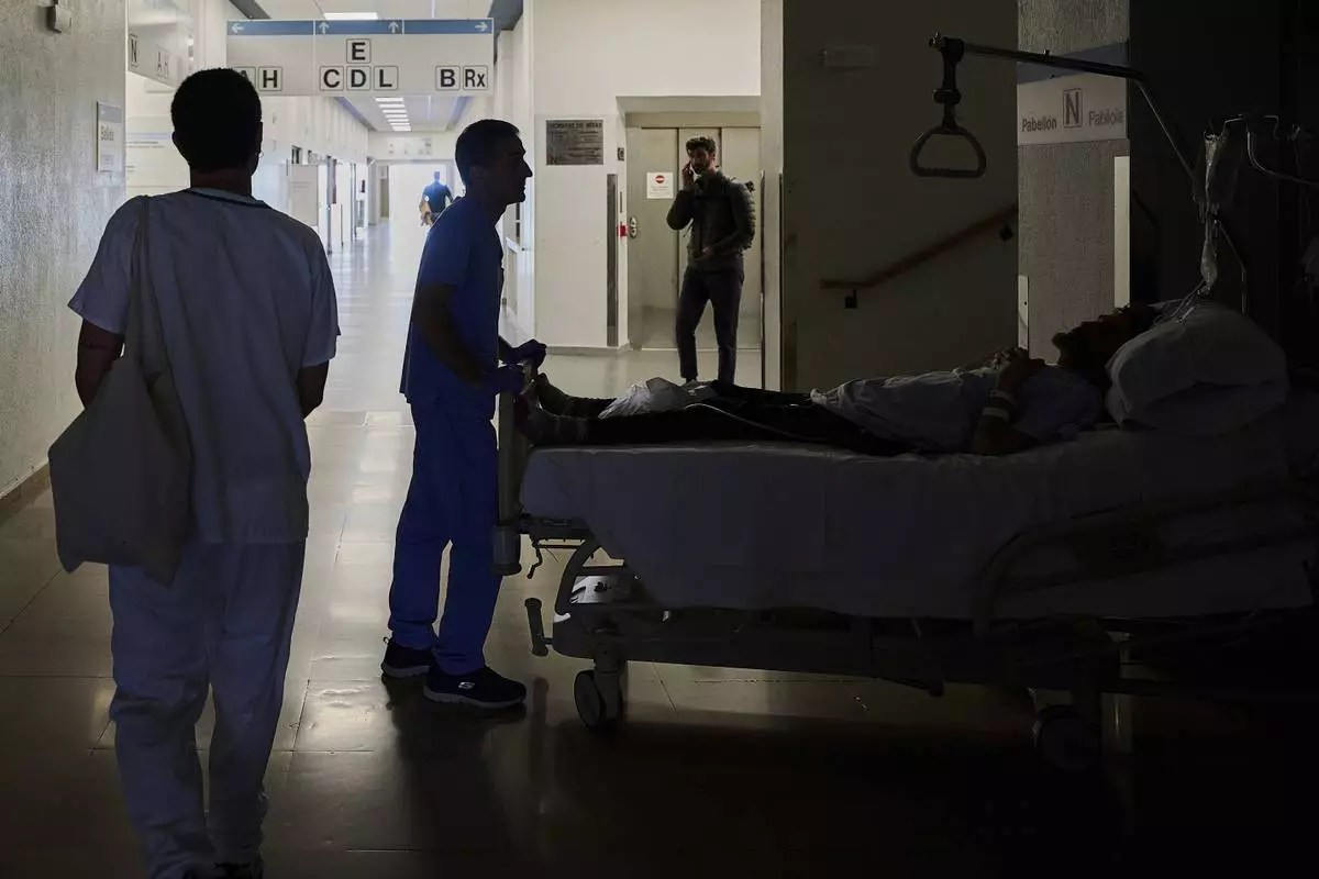 A medical staffer relocates a patient during a nationwide power outage in Pamplona, northern Spain, Monday, April 28, 2025. (AP Photo/Miguel Oses)