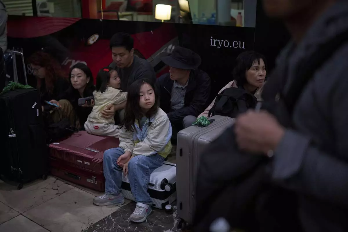 Passengers sit as they wait for news of train departures, at Sants train station in Barcelona, Spain, Tuesday, April 29, 2025. (AP Photo/Emilio Morenatti)