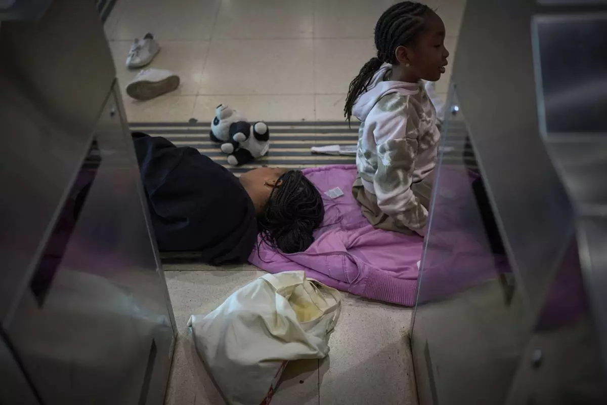 Passengers sleep and sit on the ground as they wait for news of train departures, at Sants train station in Barcelona, Spain, Tuesday, April 29, 2025. (AP Photo/Emilio Morenatti)