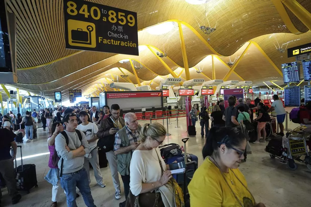 Passengers queue inside Madrid airport, during a nationwide power outage, Monday, April 28, 2025. (AP Photo/Manu Fernandez)