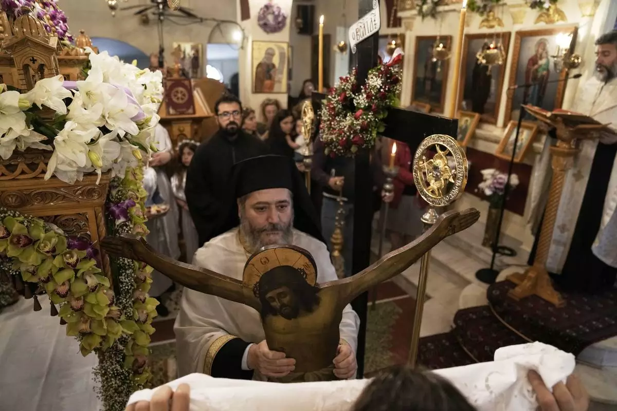 A Greek Orthodox priest holds a statue of Christ during a Good Friday reenactment of the Deposition of Jesus Christ at Agios Antonios church in the northern suburb of Chalandri during Holy Week in Athens, Greece, Friday, April 18, 2025. (AP Photo/Thanassis Stavrakis)