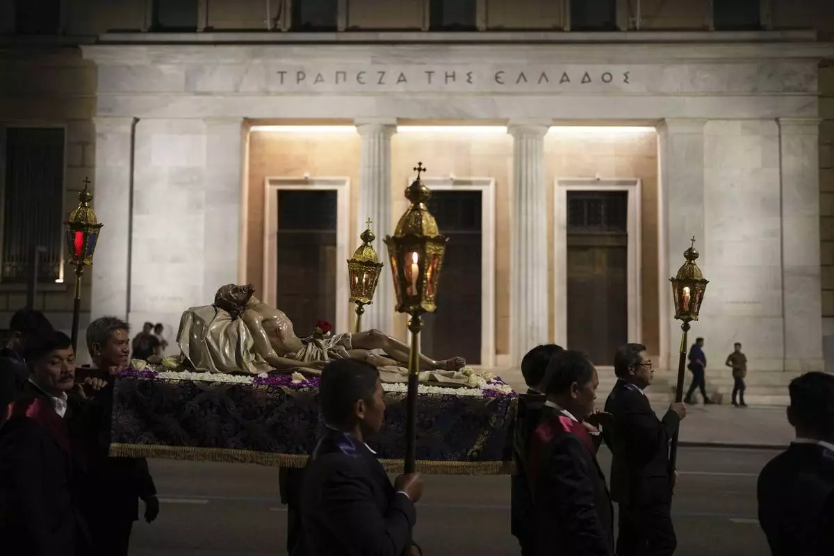 Men carrying the body of Jesus Christ pass the Bank of Greece headquarters during the Epitaph Procession of the Catholic Cathedral Basilica of St Dionysius the Areopagite in Athens, Greece, Good Friday, April 18, 2025. (AP Photo/Thanassis Stavrakis)
