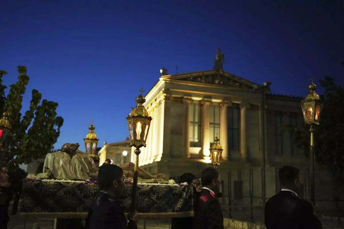 Men carrying a statue of Jesus Christ pass the Athens Academy during the Epitaph Procession of the Catholic Cathedral Basilica of St Dionysius the Areopagite in Athens, Greece, Good Friday, April 18, 2025. (AP Photo/Thanassis Stavrakis)
