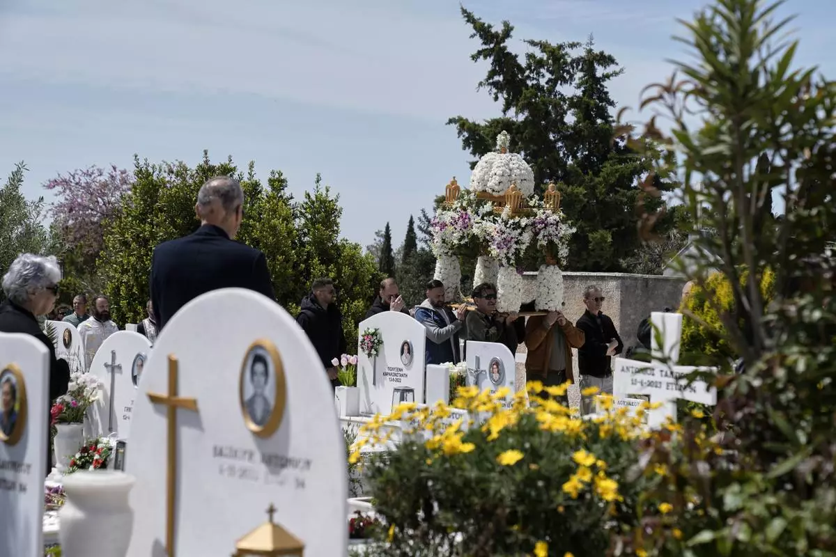 The procession of Jesus' funeral bier, known as the "Epitaph" in Greek, pass next to graves at a cemetery in Chalandri suburb, in northern Athens, Greece, Friday, April 18, 2025. (AP Photo/Thanassis Stavrakis)