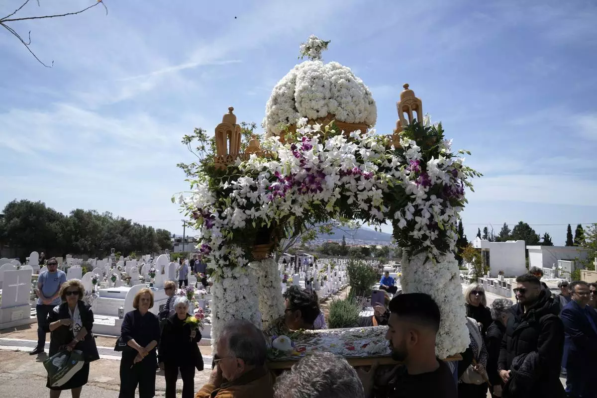 The procession of Jesus' funeral bier, known as the "Epitaph" in Greek, pass next to graves at a cemetery in Chalandri suburb, in northern Athens, Greece, Friday, April 18, 2025. (AP Photo/Thanassis Stavrakis)