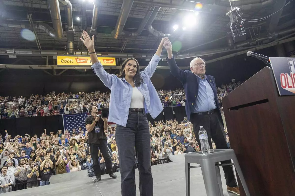 Rep. Alexandra Ocasio-Cortez, D-N.Y., holds hands with Sen. Bernie Sanders, I-Vt., during a "Fighting Oligarchy" event at the Ford Idaho Center in Nampa, Idaho, Monday, April 14, 2025. (AP Photo/Kyle Green)