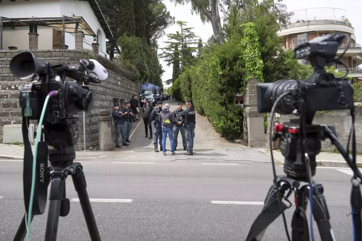 Police and reporters stand outside the Omani Embassy in Rome during a closed-door meeting between U.S. and Iranian delegations to discuss Tehran's rapidly advancing nuclear program, Saturday, April 19, 2025. (AP Photo/Andrew Medichini)