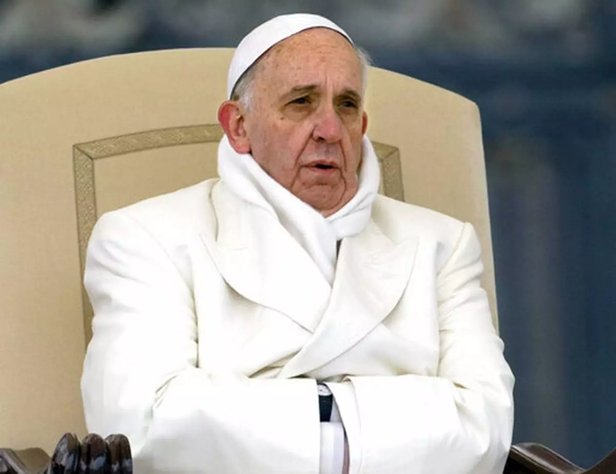 FILE - Pope Francis tries to keep himself warm as he attends his weekly general audience in St. Peter's Square at the Vatican, Wednesday, Nov. 27, 2013. (AP Photo/Alessandra Tarantino, File )