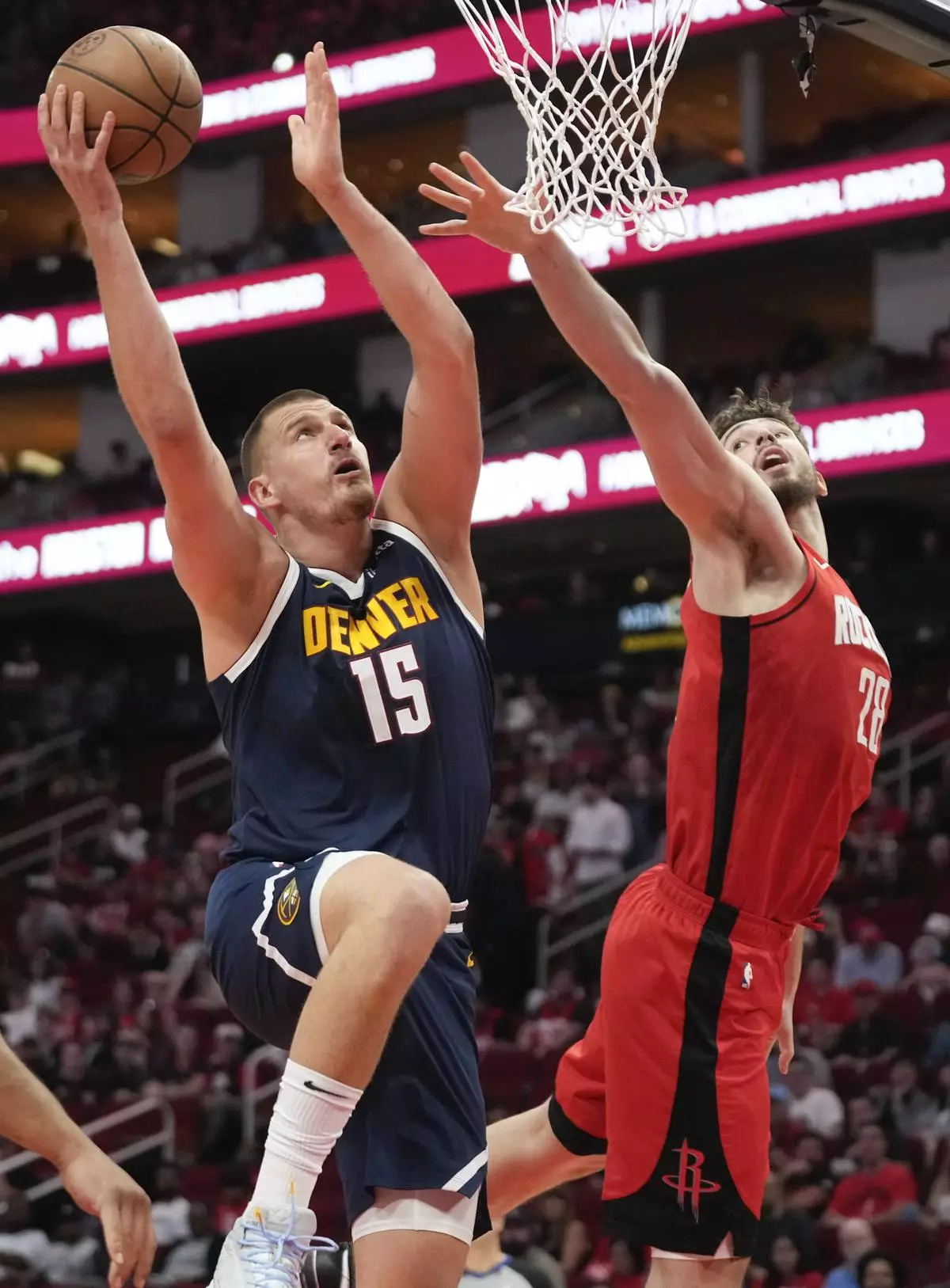 Denver Nuggets center Nikola Jokic (15) shoots as Houston Rockets center Alperen Sengun defends during the first half of an NBA basketball game Sunday, April, 13, 2025, in Houston. (AP Photo/Eric Christian Smith)