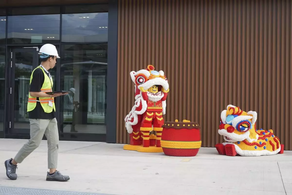 A worker walks past Lego characters in Vietnamese traditional lion dance costumes displayed at Lego factory in Binh Duong, Vietnam Wednesday, April 2, 2025. (AP Photo/Hau Dinh)