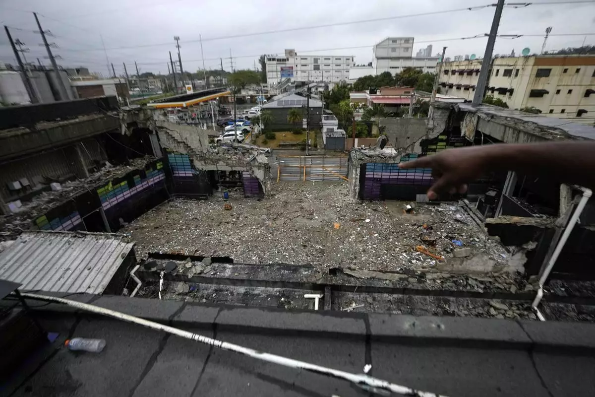 A person points to the inside of the Jet Set nightclub days after its roof collapsed, killing more than 200 people, in Santo Domingo, Dominican Republic, Friday, April 11, 2025. (AP Photo/Matias Delacroix)