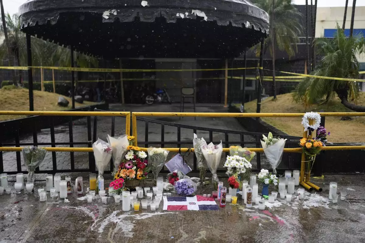 Flowers and candles sit outside the Jet Set nightclub, placed in memory of the more than 200 people who died when its roof collapsed in Santo Domingo, Dominican Republic, Friday, April 11, 2025. (AP Photo/Matias Delacroix)