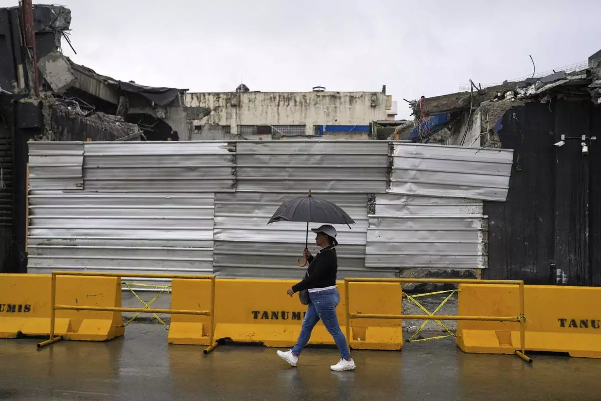 A woman walks past the rubble of Jet Set nightclub days after its roof collapsed, killing more than 200 people, in Santo Domingo, Dominican Republic, Friday, April 11, 2025. (AP Photo/Matias Delacroix)