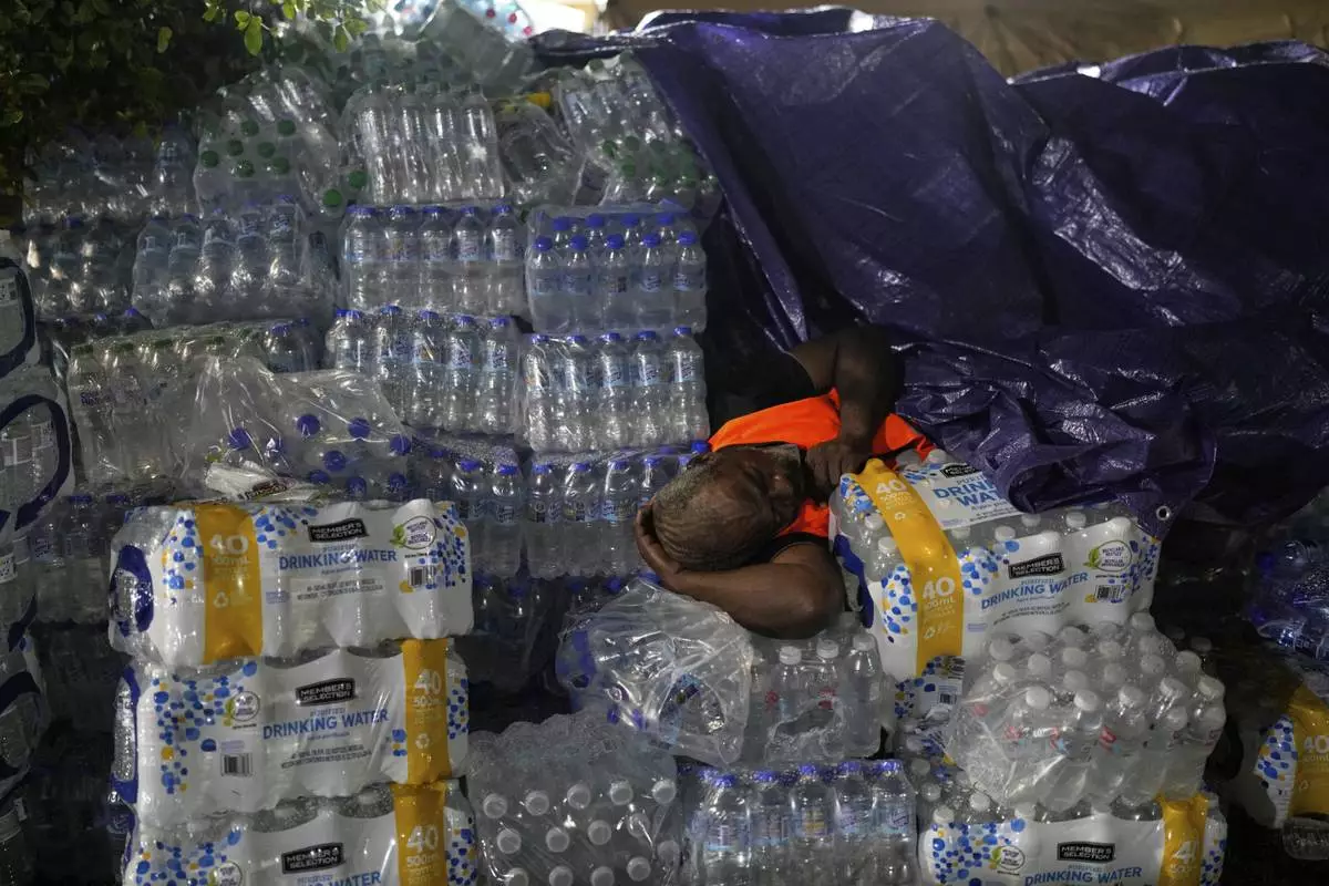 A man sleeps on bottles of water in Santo Domingo, Dominican Republic, Thursday, April 10, 2025, in front of the Jet Set nightclub after its roof collapsed during a merengue concert. (AP Photo/Matias Delacroix)
