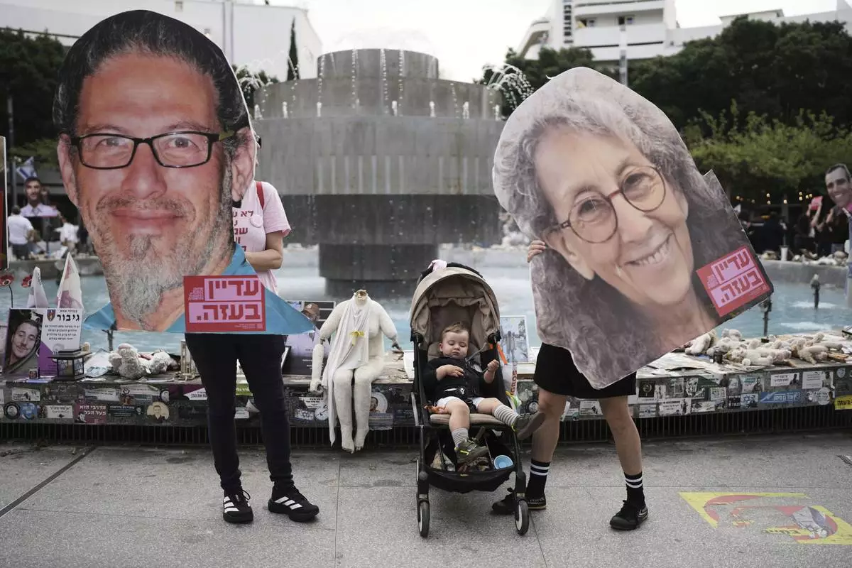 People hold photos of hostages held in Gaza, ahead of a two-minute siren marking the annual Israeli Holocaust Remembrance Day, in Tel Aviv, Israel, Thursday, April 24, 2025. (AP Photo/Oded Balilty)