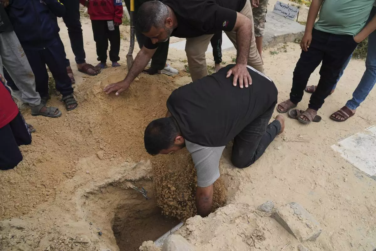 Fayez Zidan, lowers into the grave his 15-days-old premature infant Sila Zidane after she died at Nasser Hospital in Khan Younis, at the cemetery in Deir al-Balah, Gaza, on Wednesday, April 23, 2025. (AP Photo/Abdel Kareem Hana)