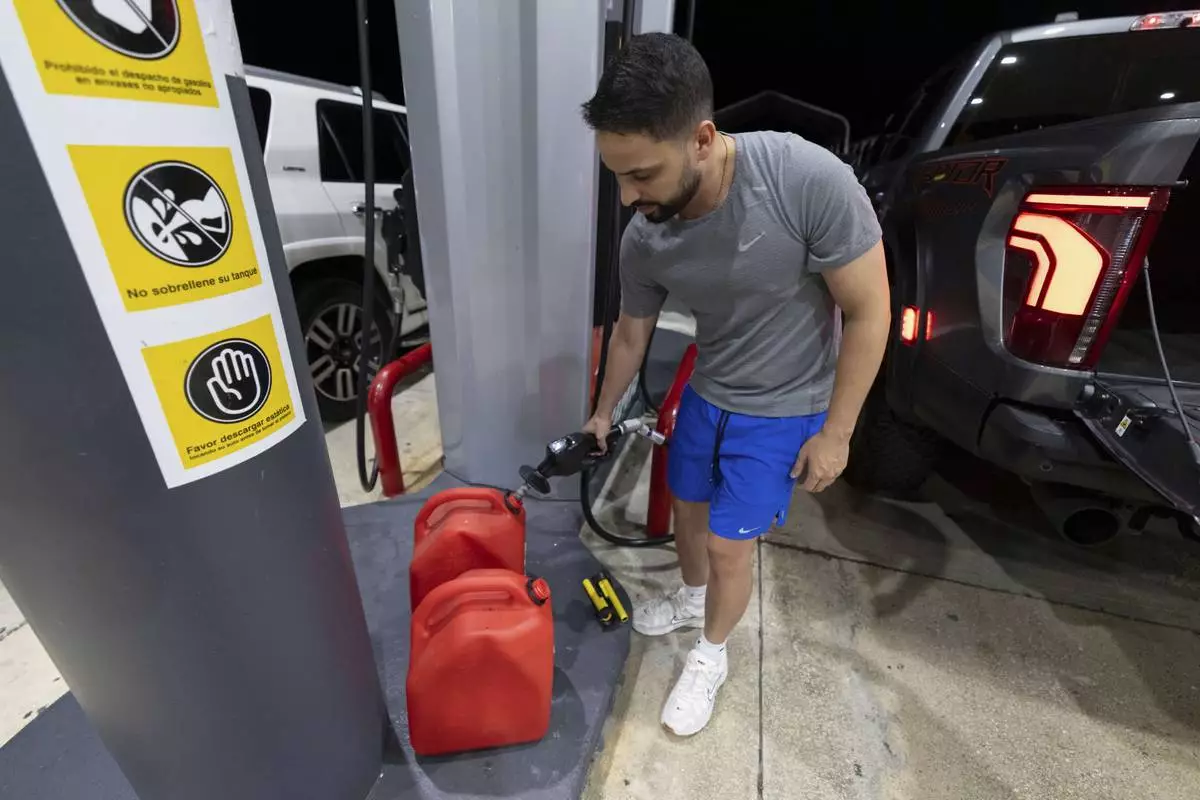A local fills fuel containers at a gas station in San Juan, Puerto Rico, during an island-wide blackout, Wednesday, April 16, 2025. (AP Photo/Alejandro Granadillo)