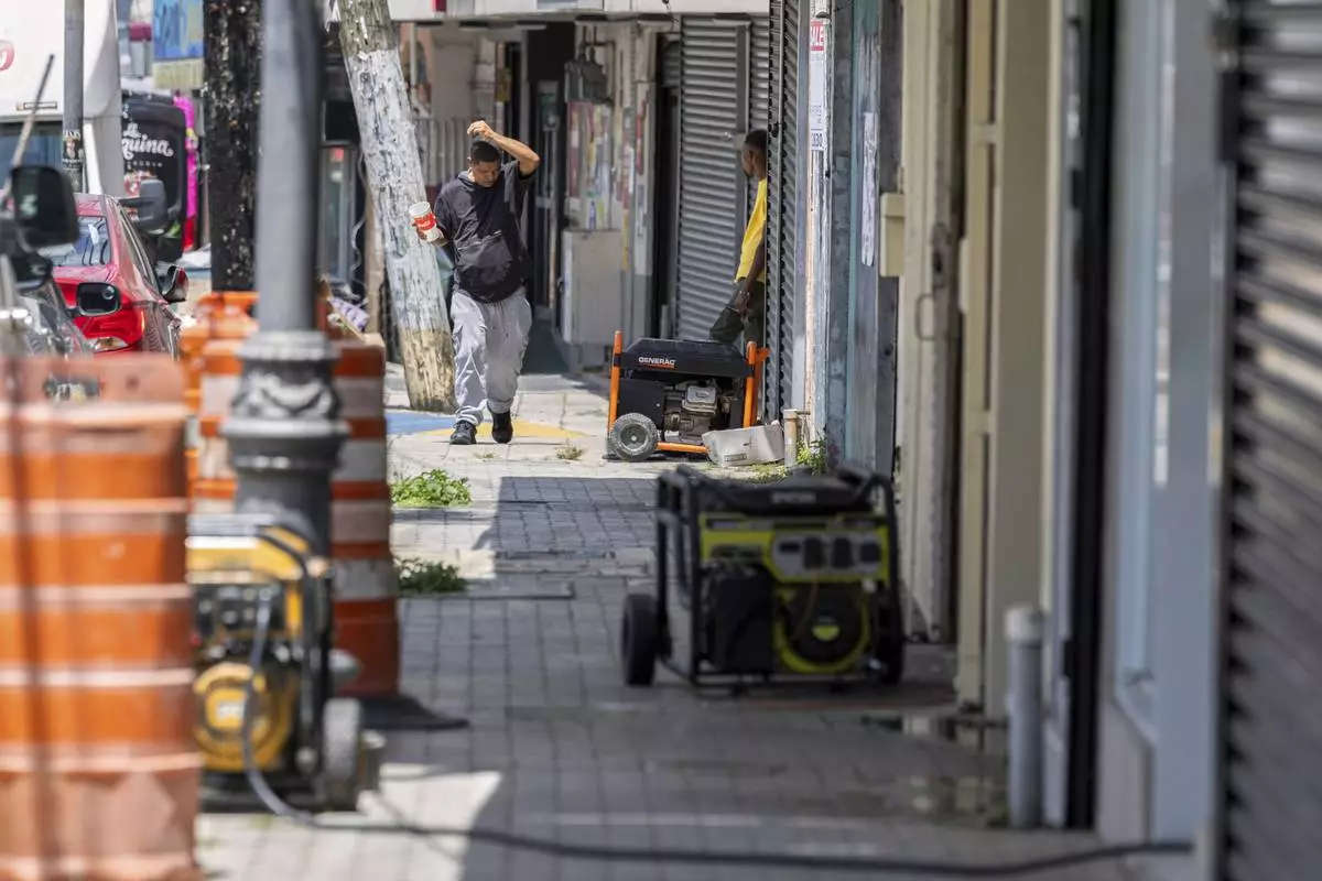 Generators line the sidewalk of a commercial street in Barrio Obrero as shops try to remain open during a prolonged power outage in San Juan, Puerto Rico, Thursday, April 17, 2025. (AP Photo/Alejandro Granadillo)