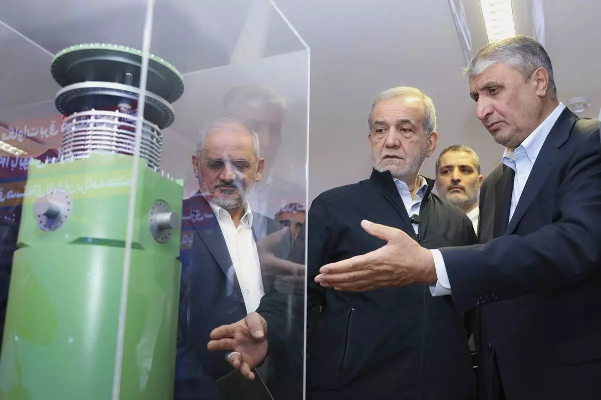 In this photo released by the Iranian Presidency Office, President Masoud Pezeshkian, second right, listens to head of Atomic Energy Organization of Iran Mohammad Eslami as he visits an exhibition of Iran's nuclear achievements, in Tehran, Iran, Wednesday, April 9, 2025. (Iranian Presidency Office via AP)
