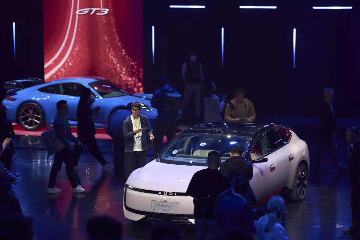 Attendees look at the latest cars from Volkswagen Group during the media night ahead of the Auto Show in Shanghai, Tuesday, April 22, 2025. (AP Photo/Ng Han Guan)