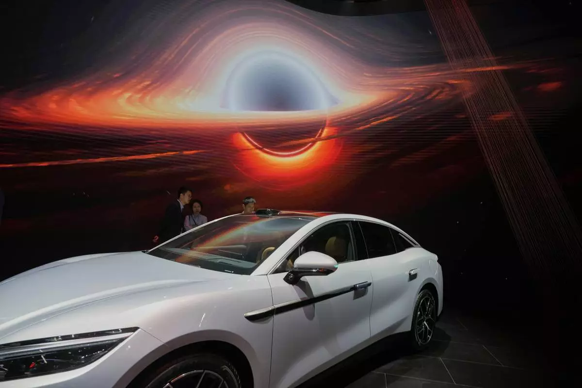 Visitors look at the Han L EV model from BYD during the Shanghai auto show on Wednesday, April 23, 2025. (AP Photo/Ng Han Guan)
