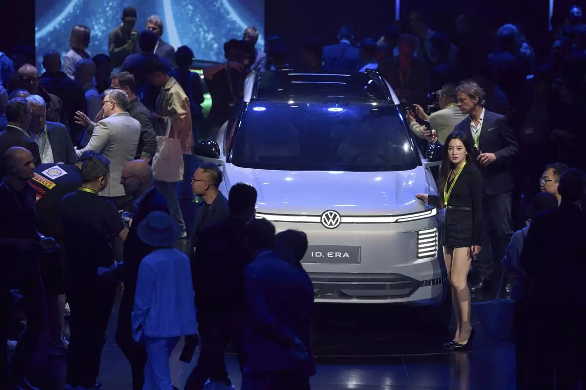 Attendees look at the latest cars from Volkswagen Group during the media night ahead of the Auto Show in Shanghai, Tuesday, April 22, 2025. (AP Photo/Ng Han Guan)