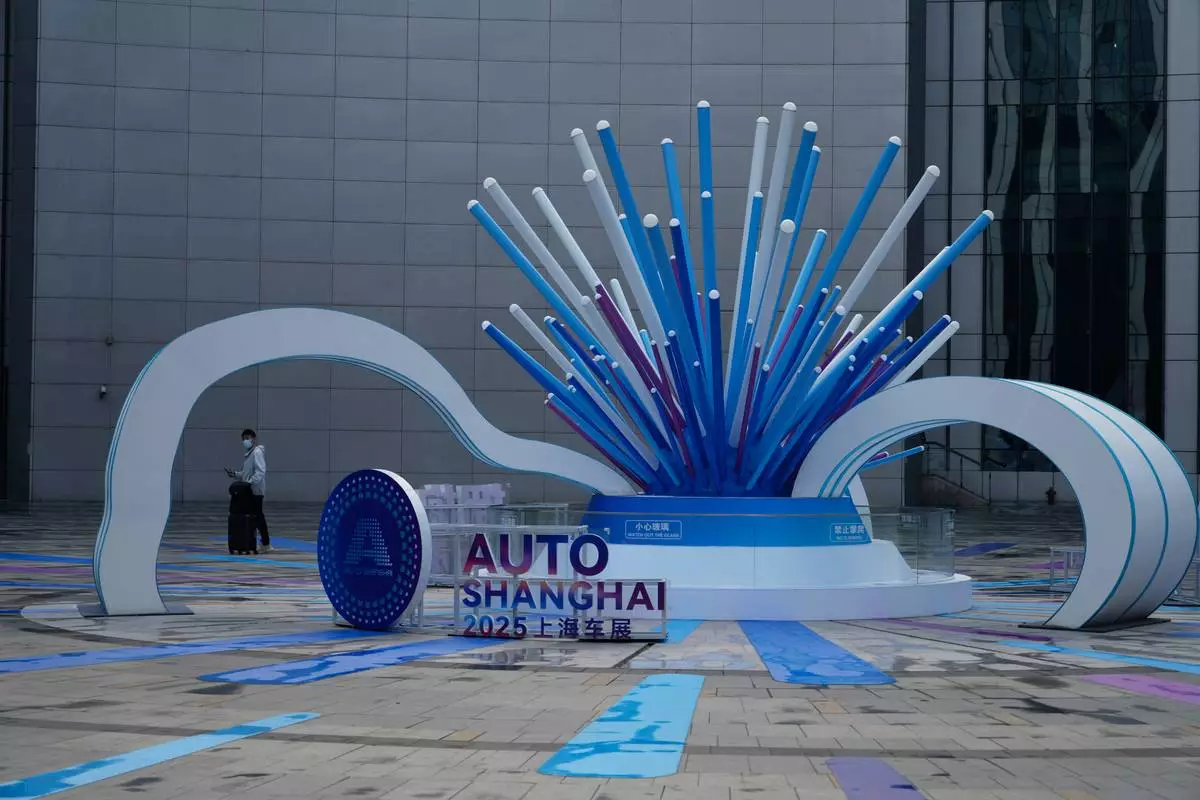 An attendee arrives to the Auto Show in Shanghai, Wednesday, April 23, 2025. (AP Photo/Ng Han Guan)