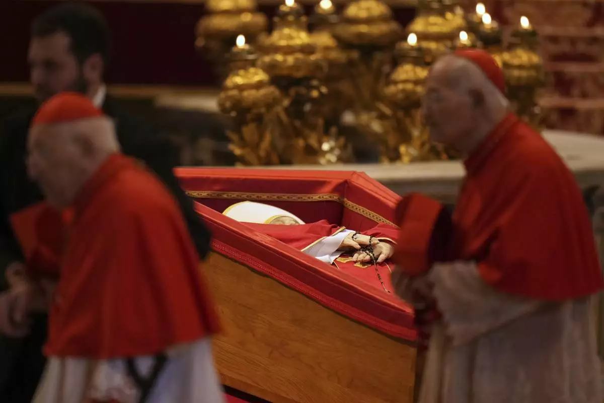 Cardinals walk past the body of Pope Francis, who will lie in state for three days, after it arrived in St. Peter's Basilica at the Vatican, Wednesday, April 23, 2025. (AP Photo/Francisco Seco)