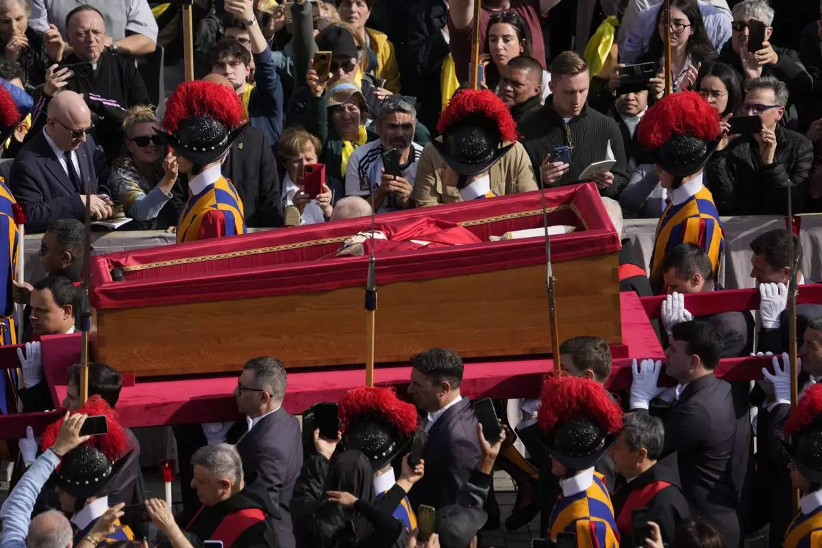 The ceremony with the Pope Francis' body, who will lie in state at St. Peter's Basilica for three days, pass through the crowd at the Vatican, Wednesday, April 23, 2025. (AP Photo/Gregorio Borgia)