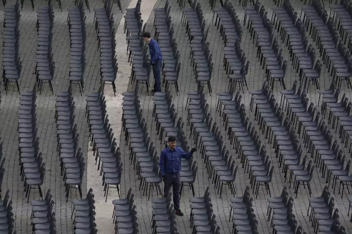 Workers adjust chairs during the preparations in St. Peter's Square ahead of the arrival of the body of Pope Francis, who will lie in state at St. Peter's Basilica for three days, at the Vatican, Wednesday, April 23, 2025. (AP Photo/Gregorio Borgia)